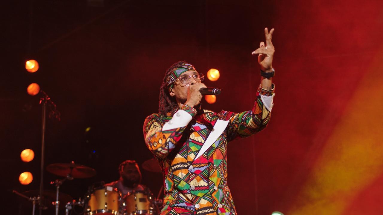 Kaf Malbar en costume coloré, live band en arrière-plan