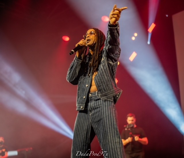 Kaf Malbar sur scène, micro à la main, lumières de concert